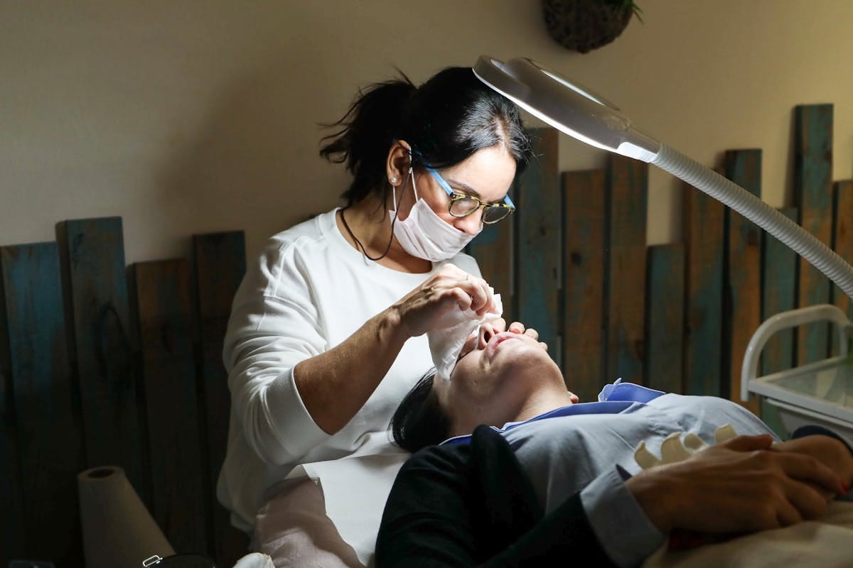 Esthetician performing facial treatment in private home studio with professional equipment