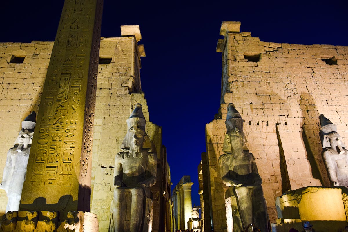Day Trip to Luxor from Cairo: An Unforgettable Journey into Ancient Egypt 2 Night view of the illuminated Luxor Temple with ancient statues and hieroglyphs.