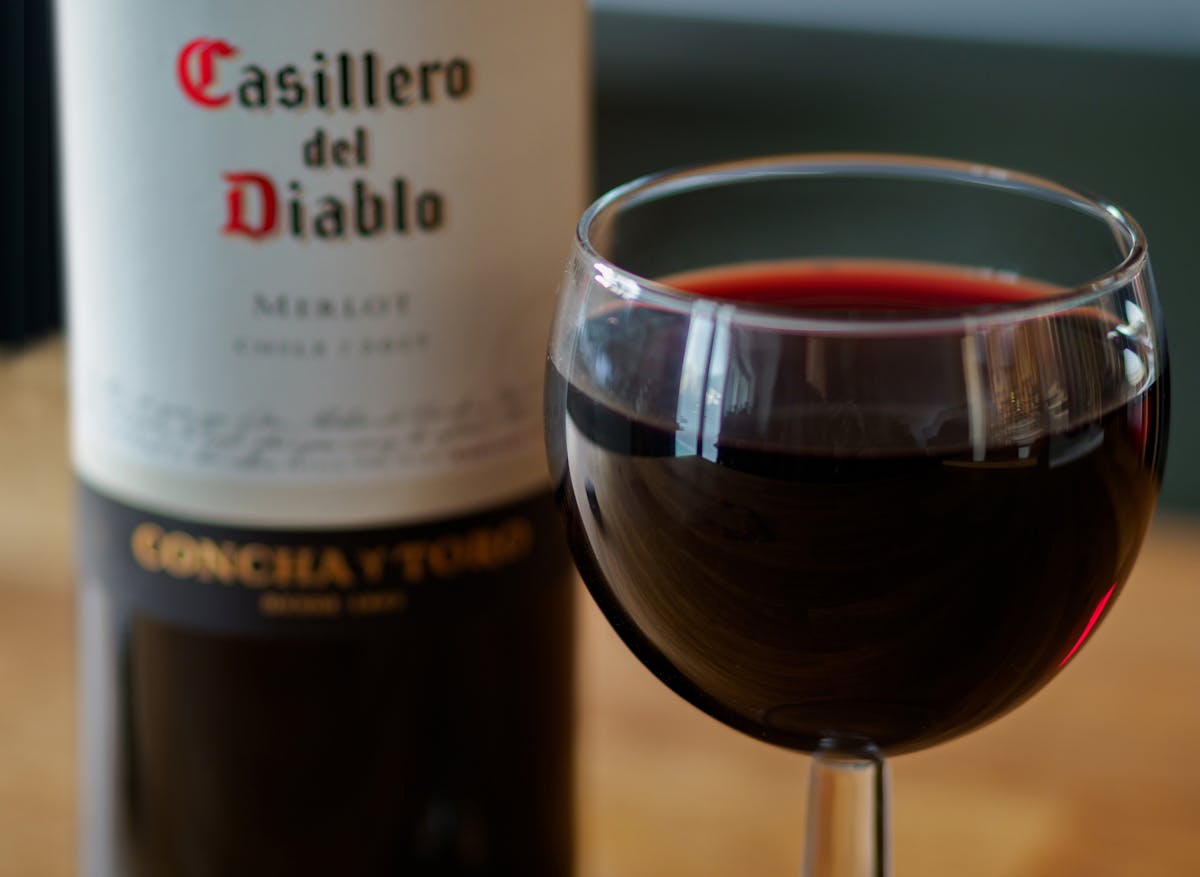 Close-up shot of a Casillero del Diablo Merlot wine bottle with a filled wine glass. Perfect for wine enthusiasts and pr