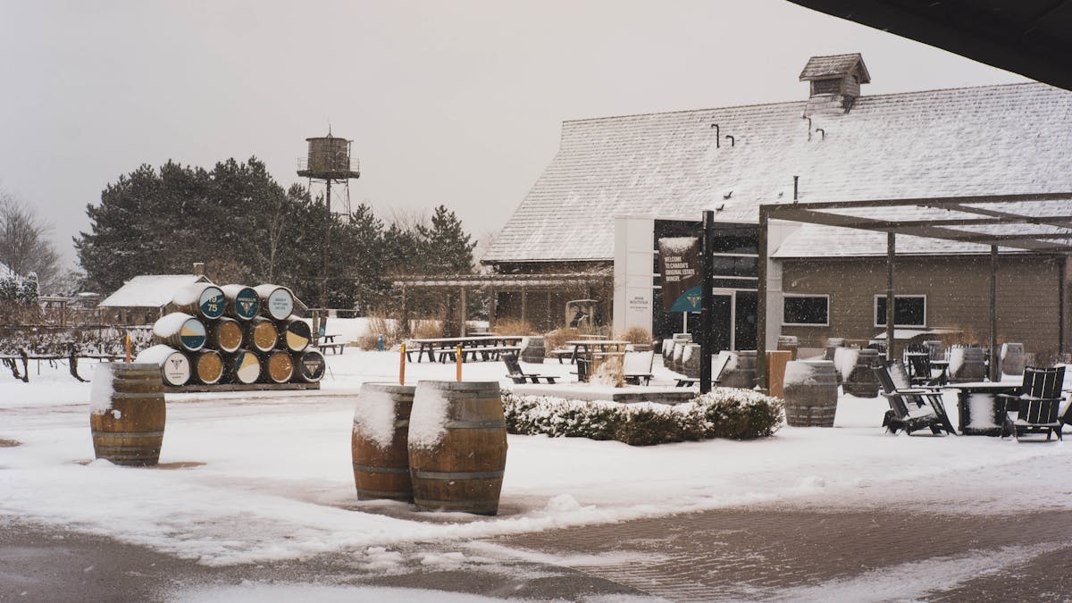 A snowy winter scene at a winery with barrels and outdoor seating.