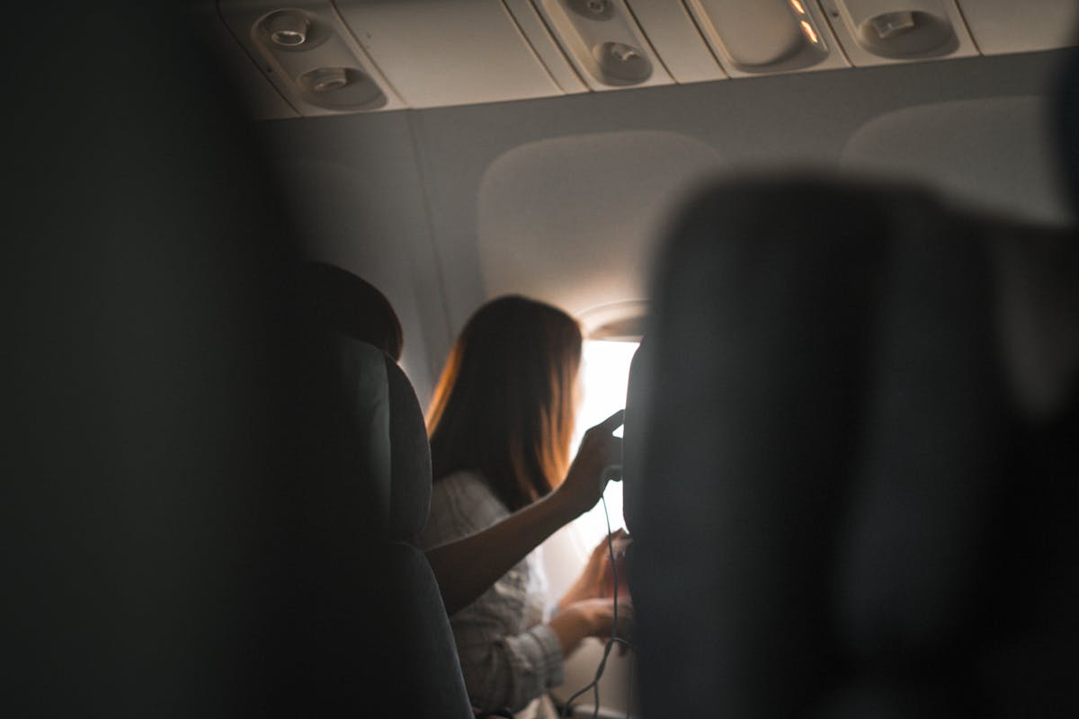 A woman looks out the airplane window, capturing the serene atmosphere of air travel.