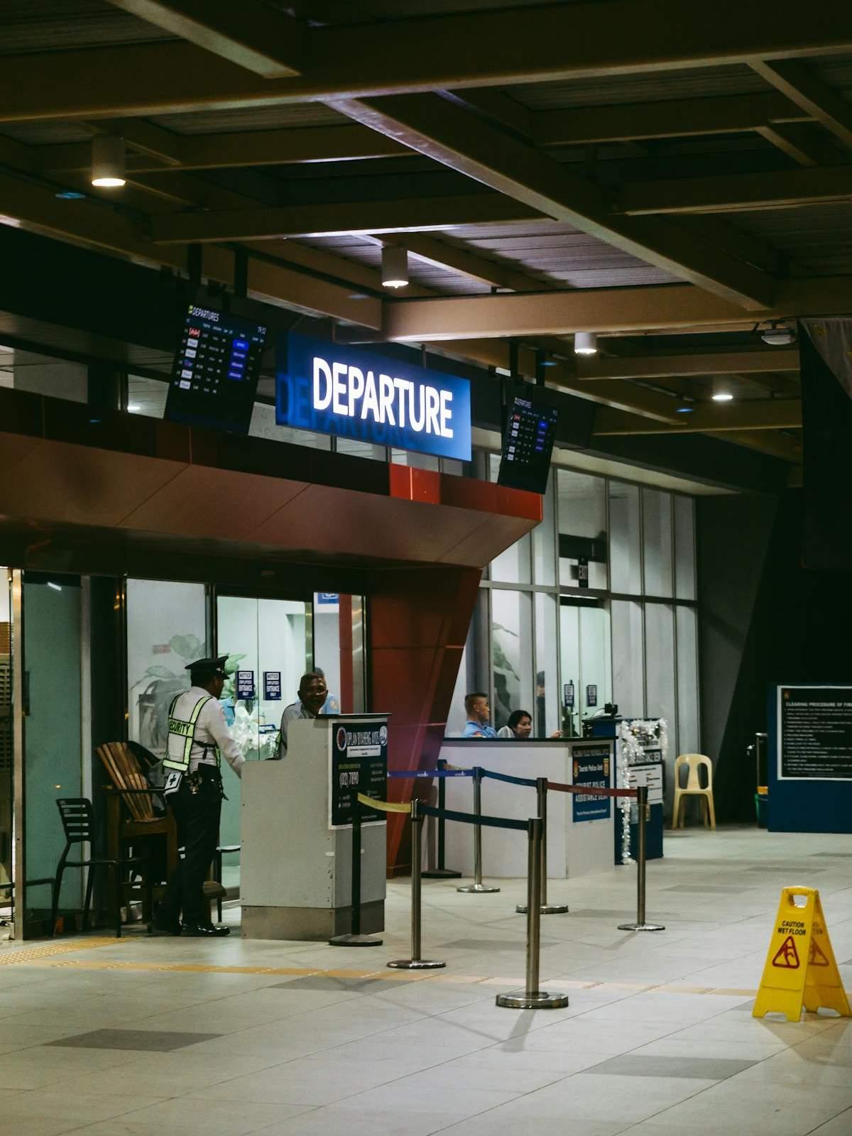 Airport departures hall with a security checkpoint entrance and queue barriers
