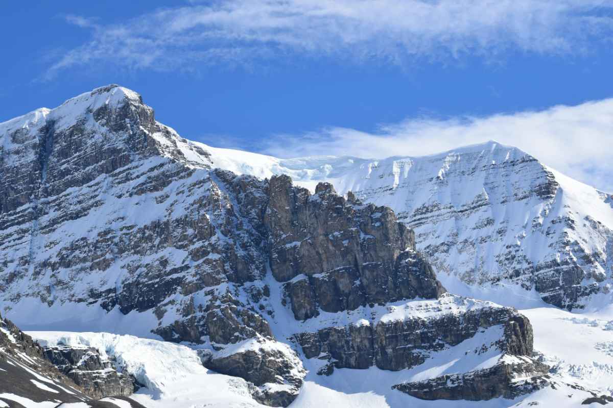 Breathtaking view of snow-covered Rocky Mountains under a vibrant blue sky in Alberta, Canada.