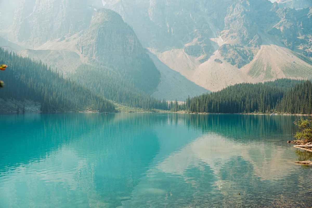 A tranquil landscape of Moraine Lake with clear turquoise waters and rugged mountain backdrop in Banff National Park.