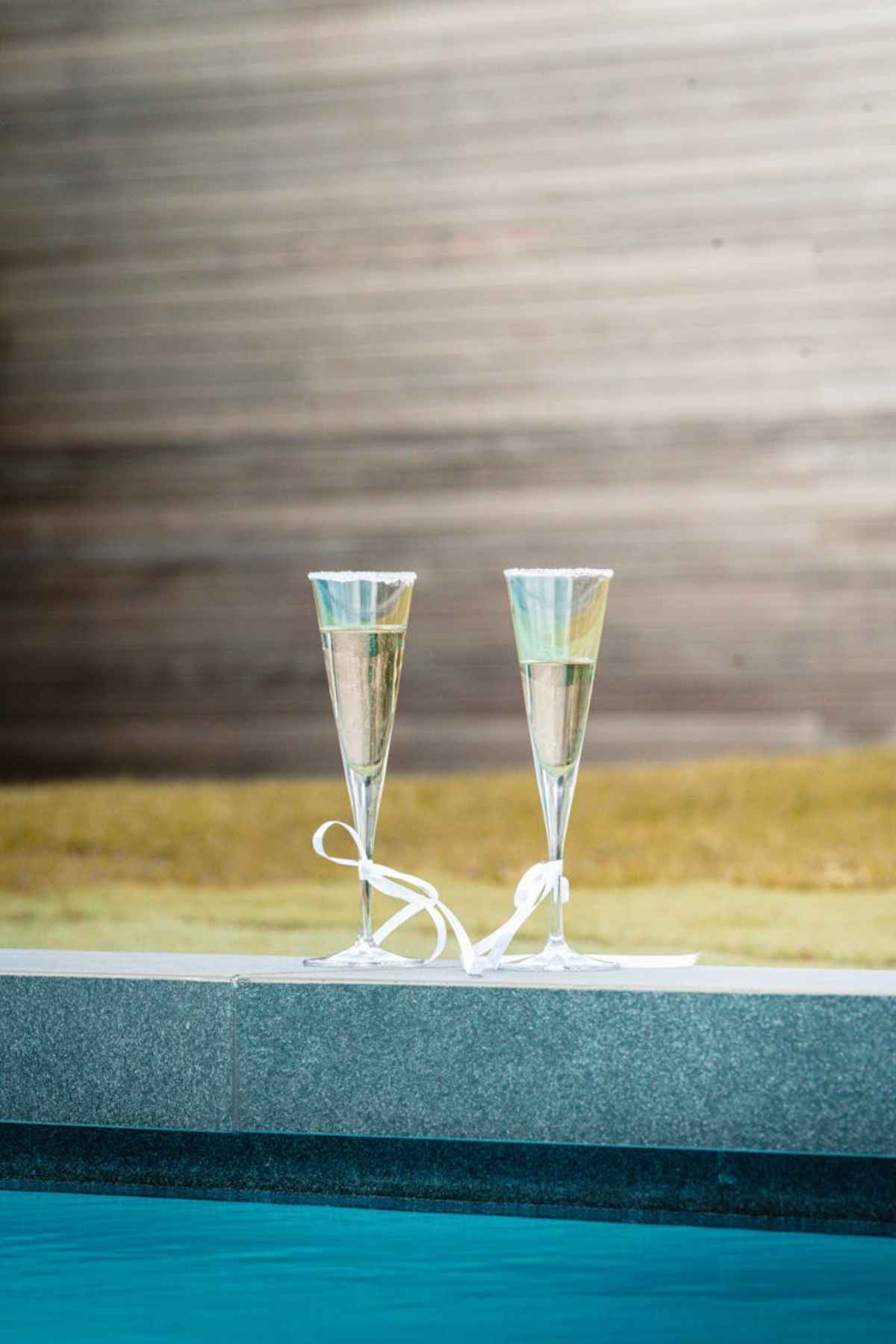 Two champagne glasses poolside luxury celebration sparkling wine