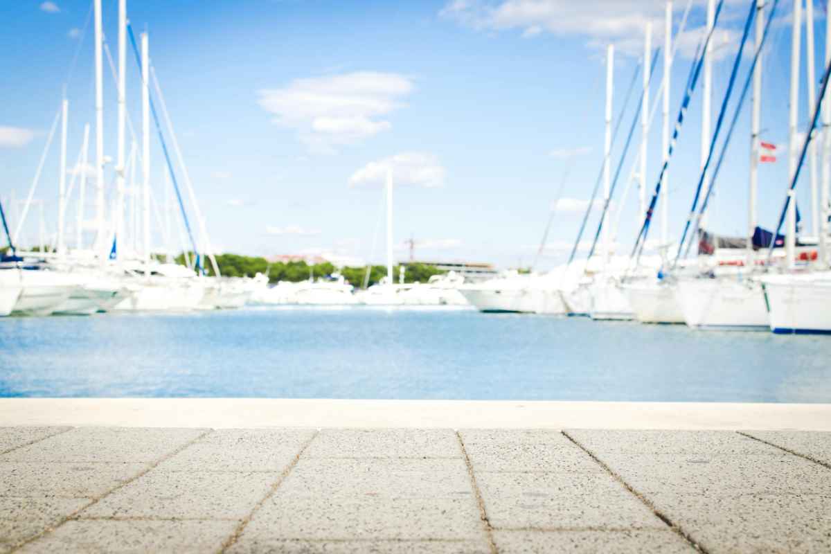 Best Yacht to Sail Around the World: Top Picks for Your Adventure 1 A scenic marina with yachts docked, clear skies, and waterfront pavement offering serene views.