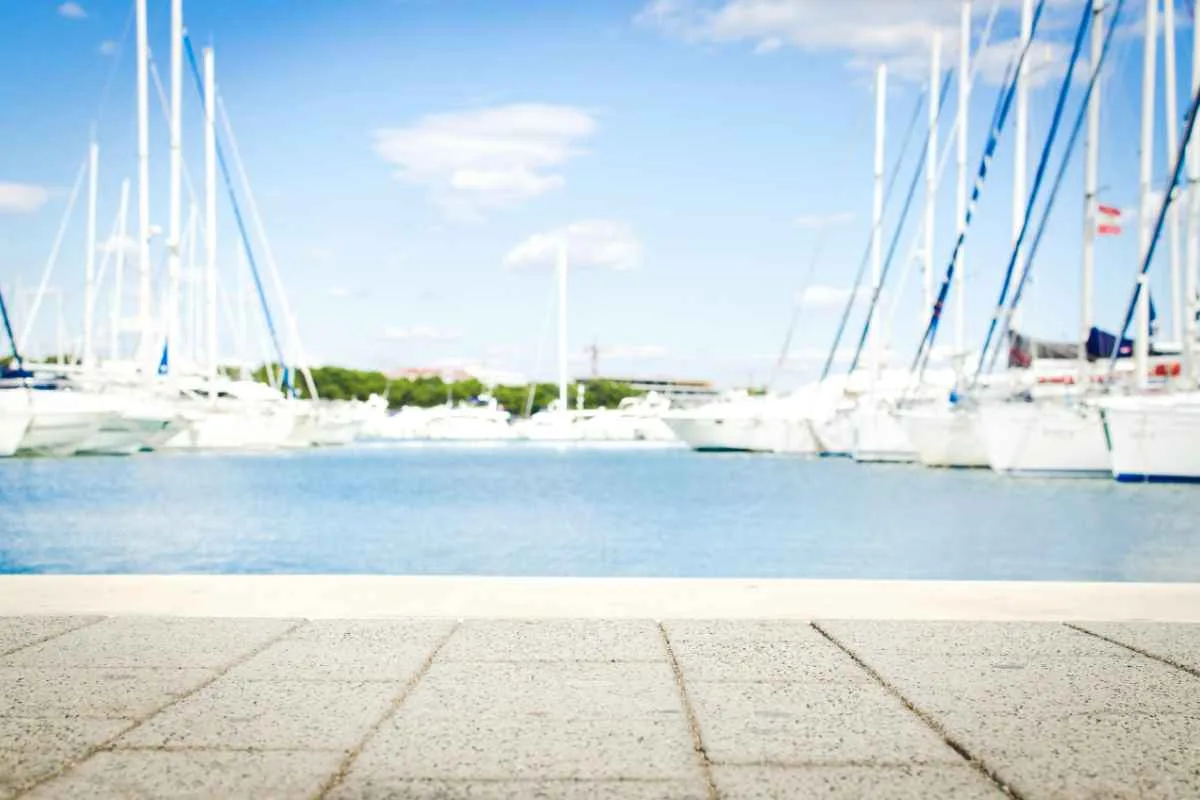 Best Yacht to Sail Around the World: Top Picks for Your Adventure 1 A scenic marina with yachts docked, clear skies, and waterfront pavement offering serene views.