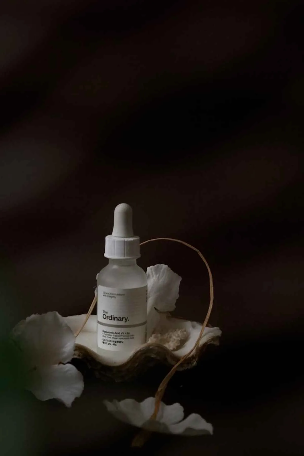 Minimalist serum bottle with white petals skincare product