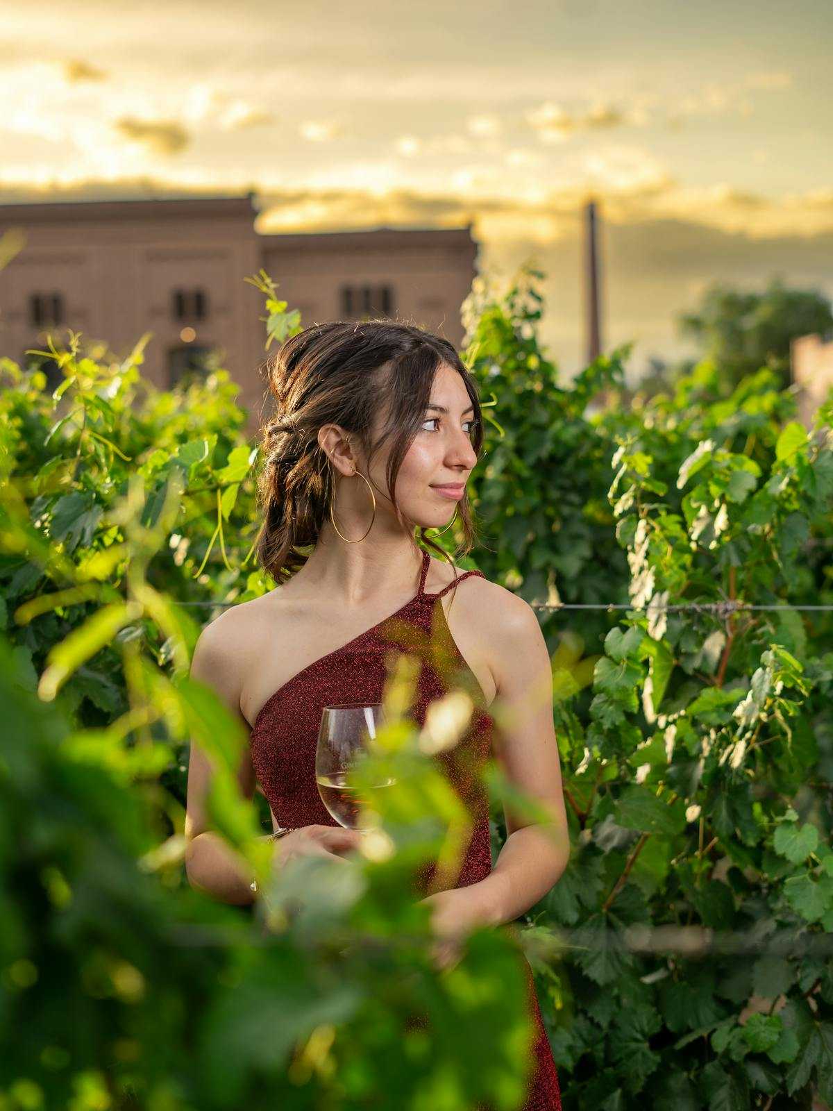 Woman holding wine glass among lush vineyard foliage in Colorado wine country