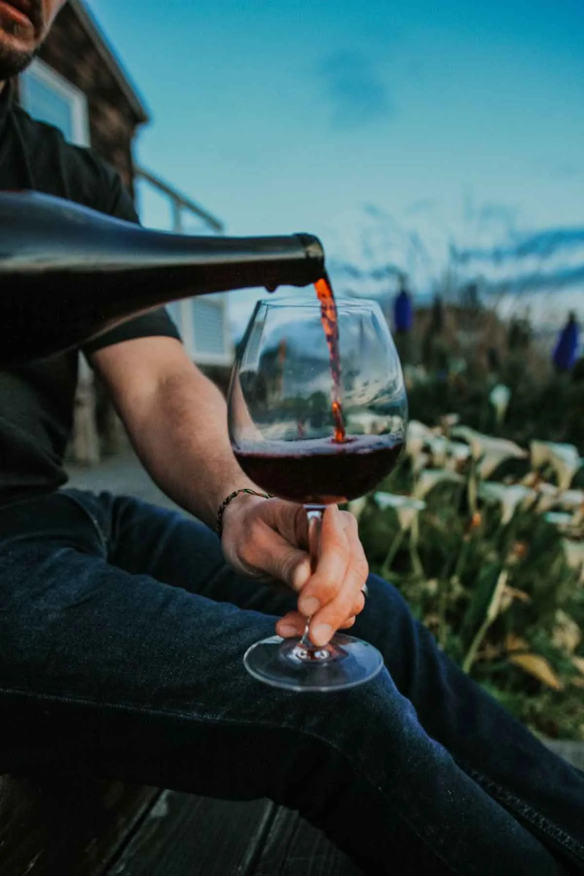 Leelanau Peninsula Wineries: Your Guide to Tasting and Tours 8 Pouring red wine into a glass while seated outdoors scenic vineyard view