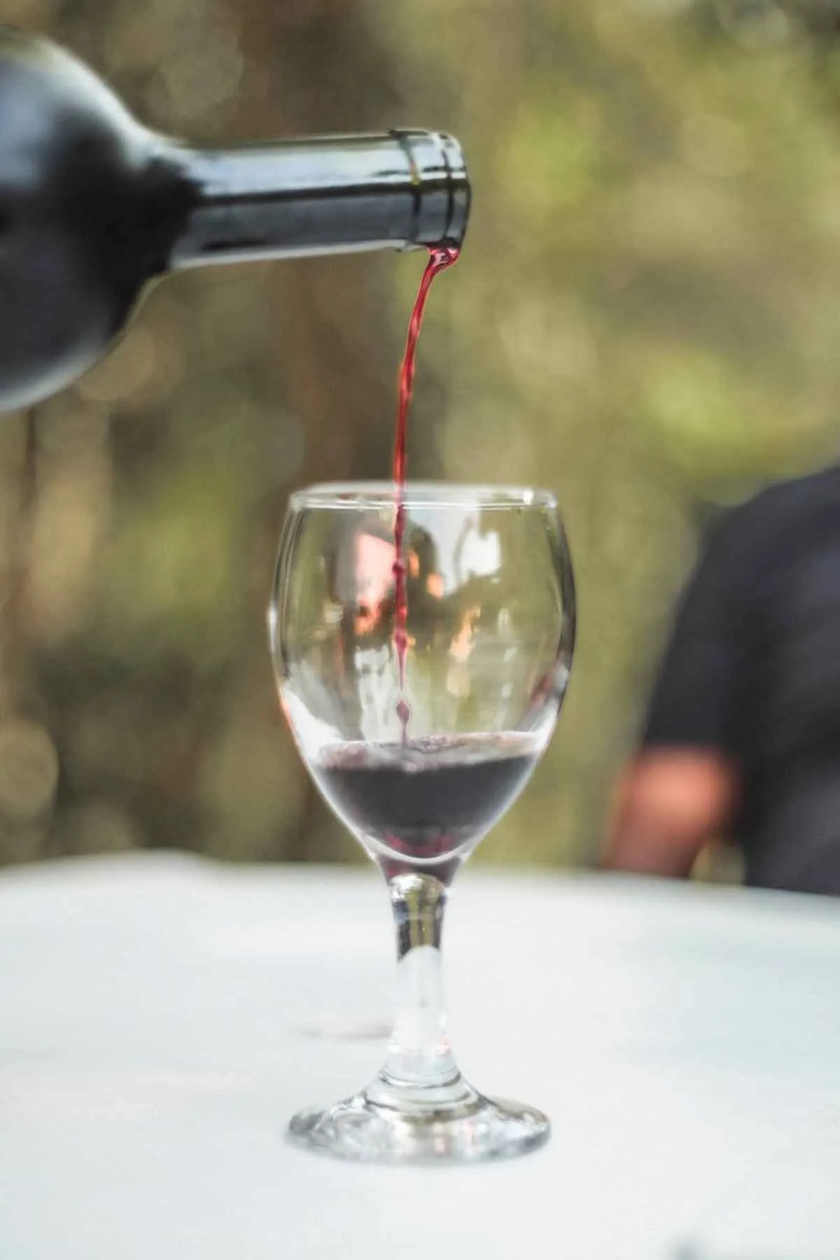 Close-up of red wine being poured from a bottle into a wineglass outdoors