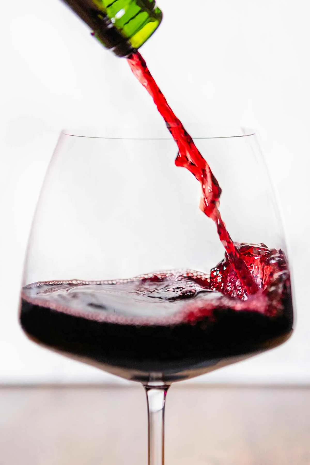 The Complete Guide to Pinot Noir: Taste, Profile, and Pairings 15 Pinot noir red wine poured into large Burgundy wine glass close up