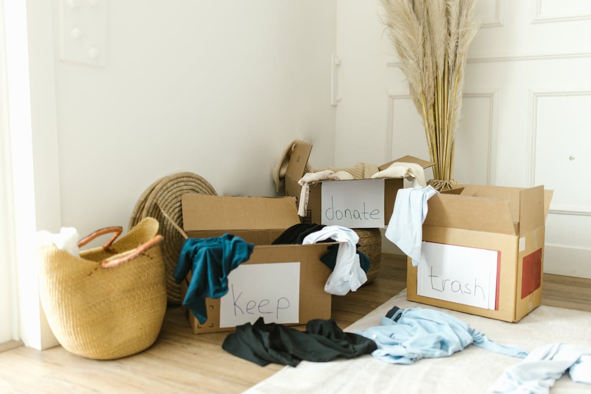 Cardboard boxes labeled keep donate and trash during a home declutter session in a clean neutral interior