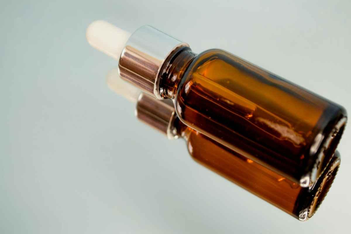 The Ultimate Guide to Skincare for Travelers: Stay Radiant Anywhere in the World 2 Amber glass serum bottle with a dropper cap lying on a pale reflective surface