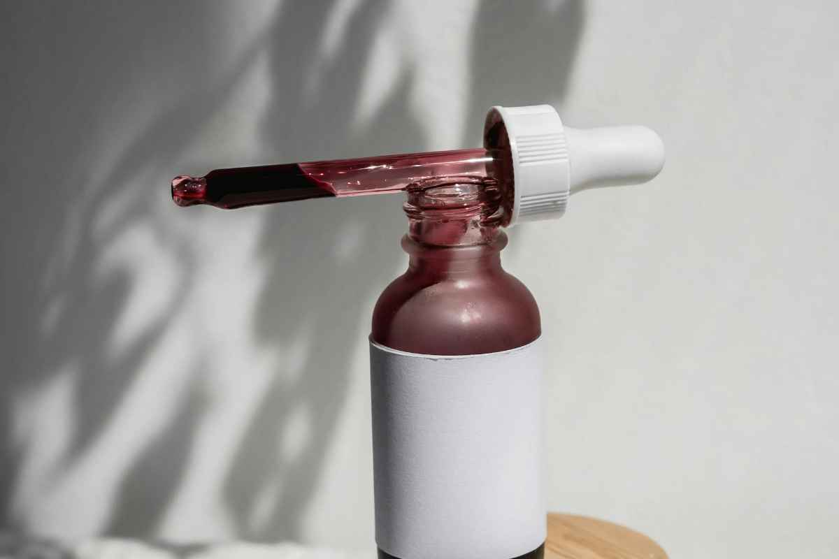 Minimalist still life of a cosmetic serum bottle with a dropper casting artistic shadows.