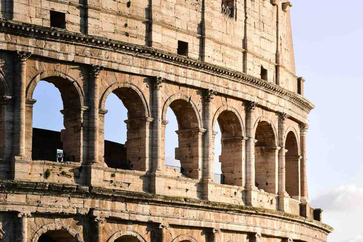 A warm, golden hour view of the Colosseum in Rome, showcasing its historic arches and stone texture.