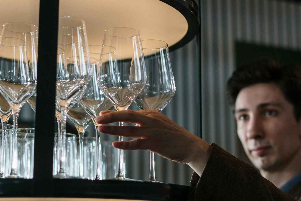 Valle de Guadalupe Wineries: A Complete Guide to Baja's Wine Country 1 A sommelier selects wine glasses from a rack in a modern bar setting. Perfect for hospitality themes.