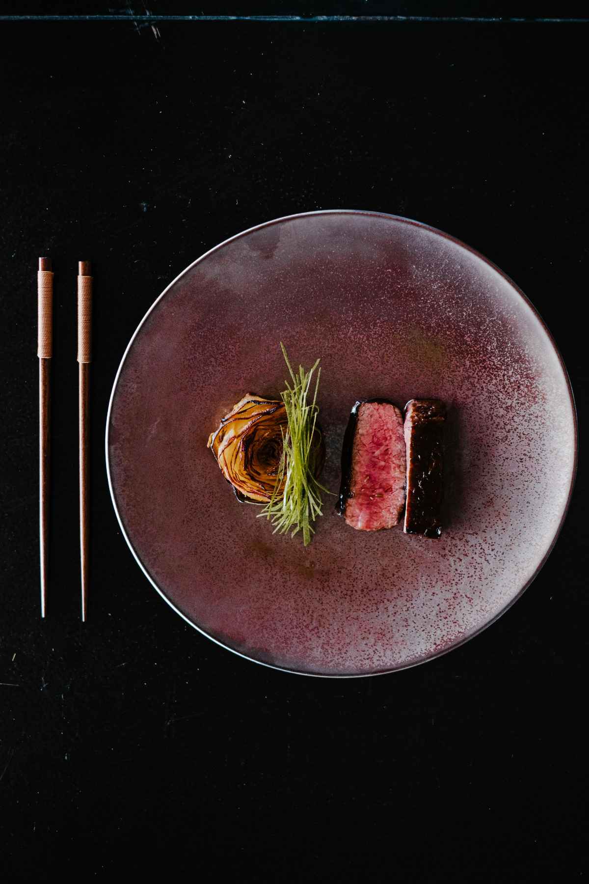 Wagyu ribeye steak elegantly plated on ceramic dish with garnish