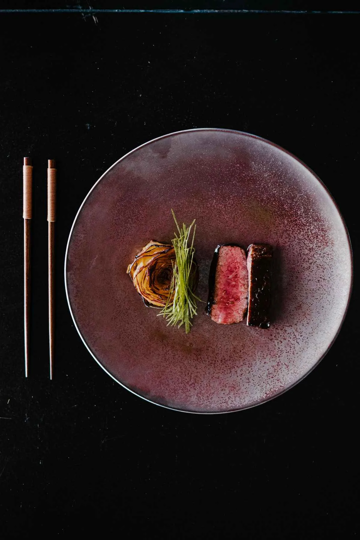 Wagyu ribeye steak elegantly plated on ceramic dish with garnish