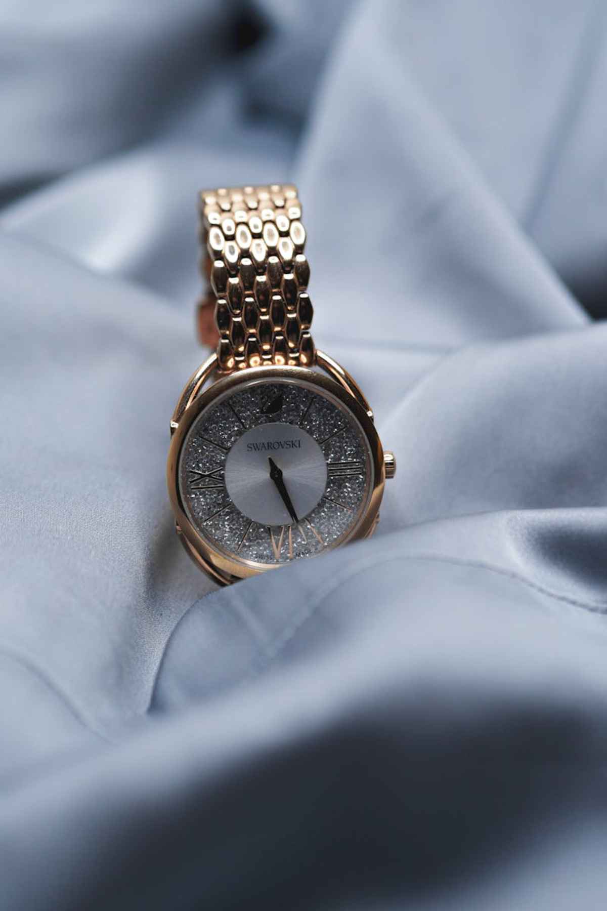 Luxury gold Swarovski wristwatch on silky gray background elegance