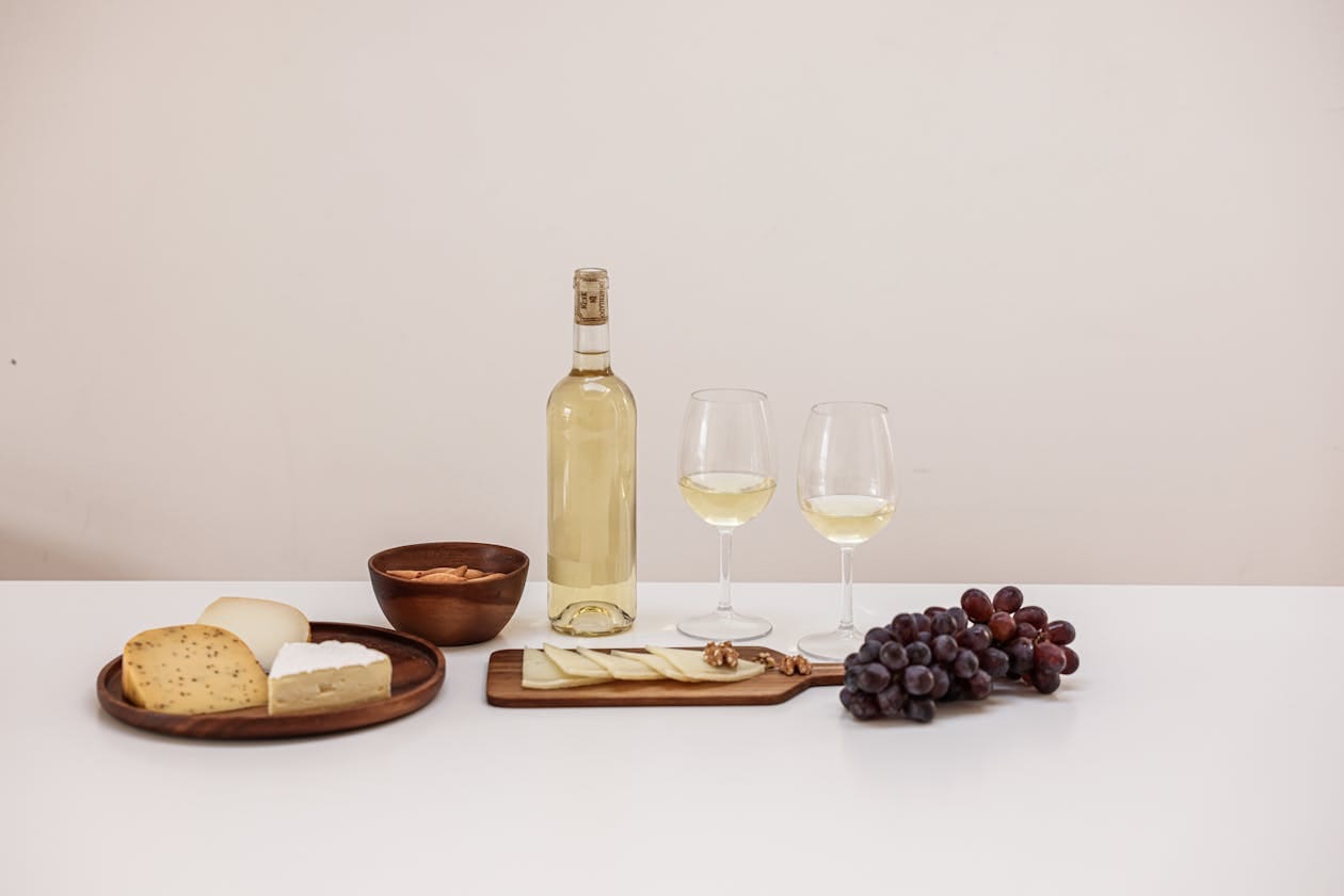 Glasses of crisp white wine with cheese and grapes, perfect pairing for caprese skewers at an elegant gathering