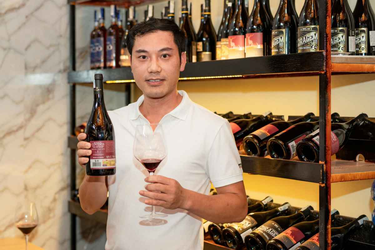 Wineries vs Vineyards: What Is the Key Difference and Why It Matters 1 Man in white shirt holding a glass and bottle of wine in a stylish wine cellar setting.