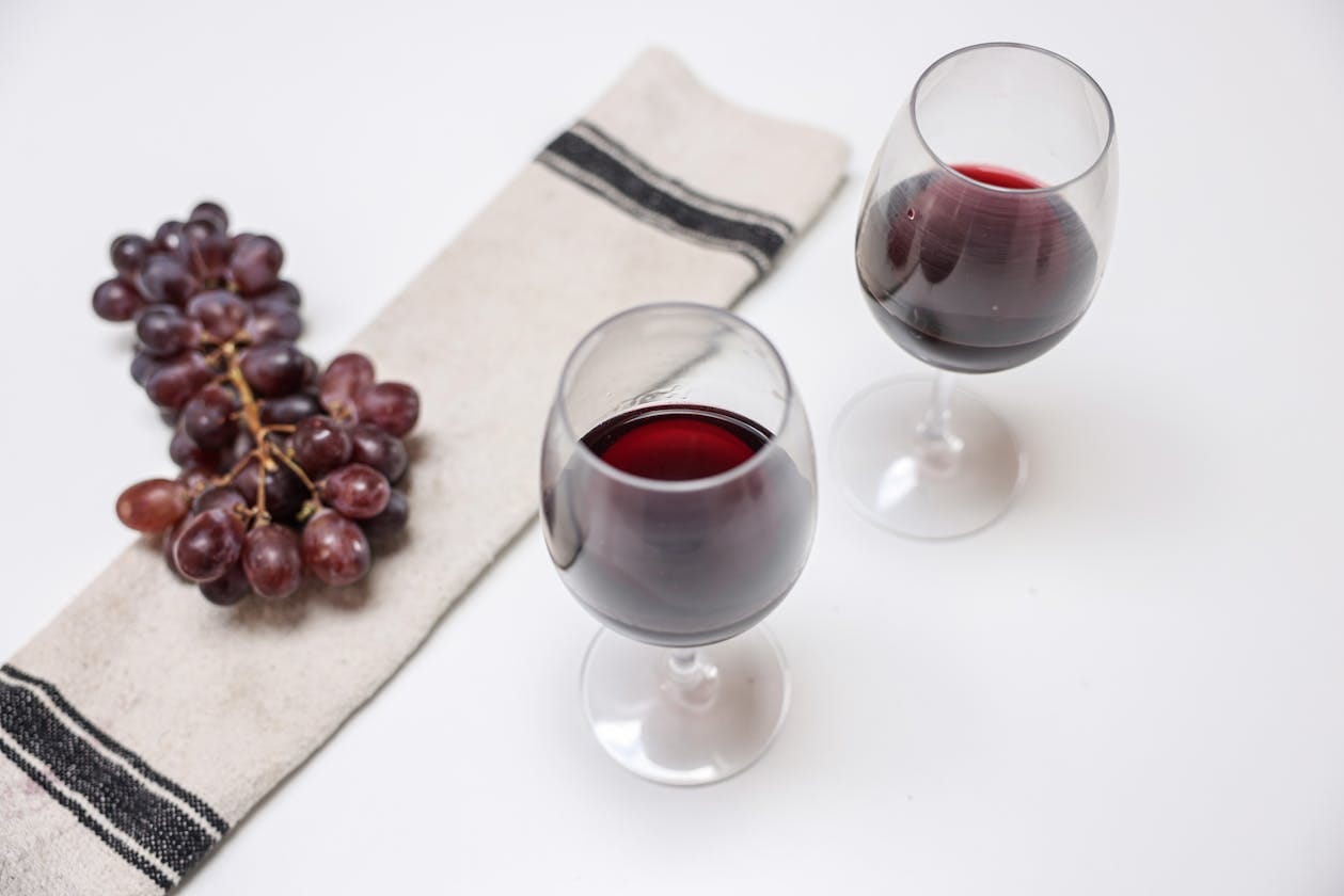 two red wine glasses with grapes for zinfandel vs merlot comparison