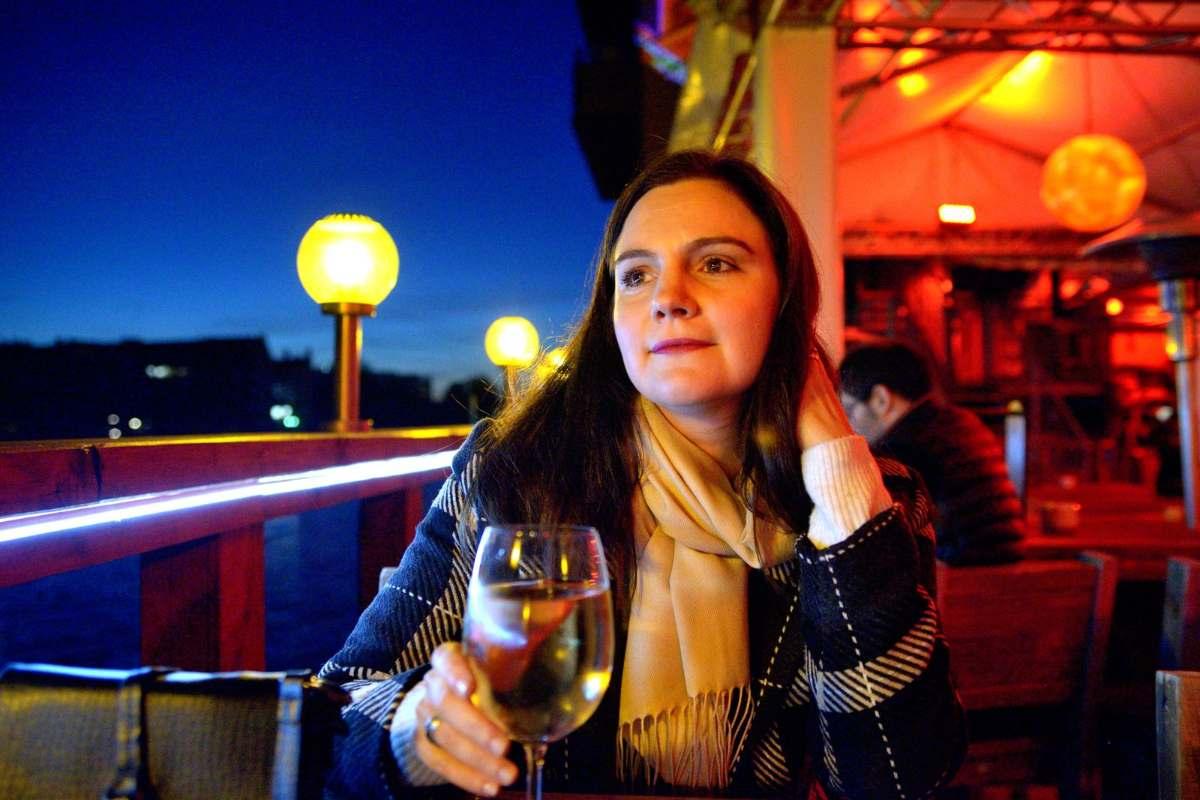 Berlin Wineries: Explore Urban Vineyards for Wine Lovers 1 Berlin wineries and wine bars: woman holding a glass of white wine on a riverside terrace in Berlin at dusk
