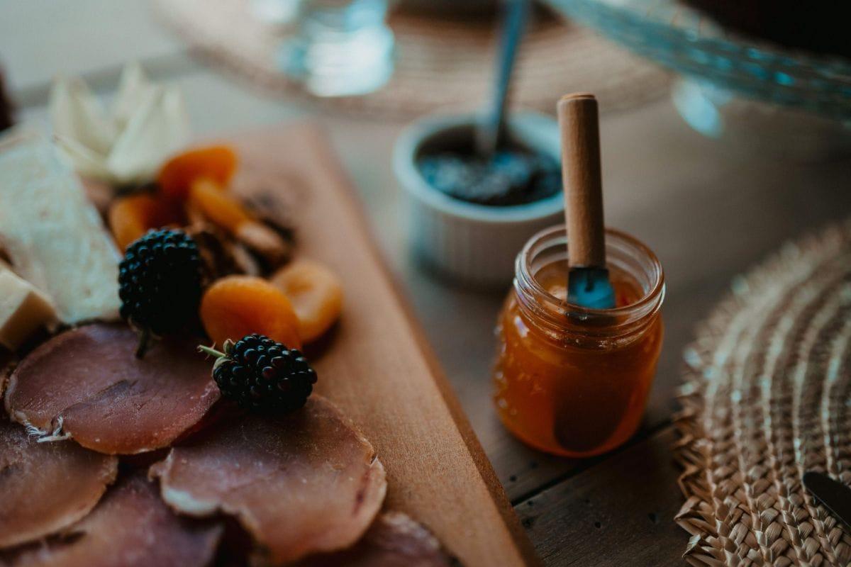Charcuterie spread with cured meat, dried apricots, blackberries, and a jar of honey