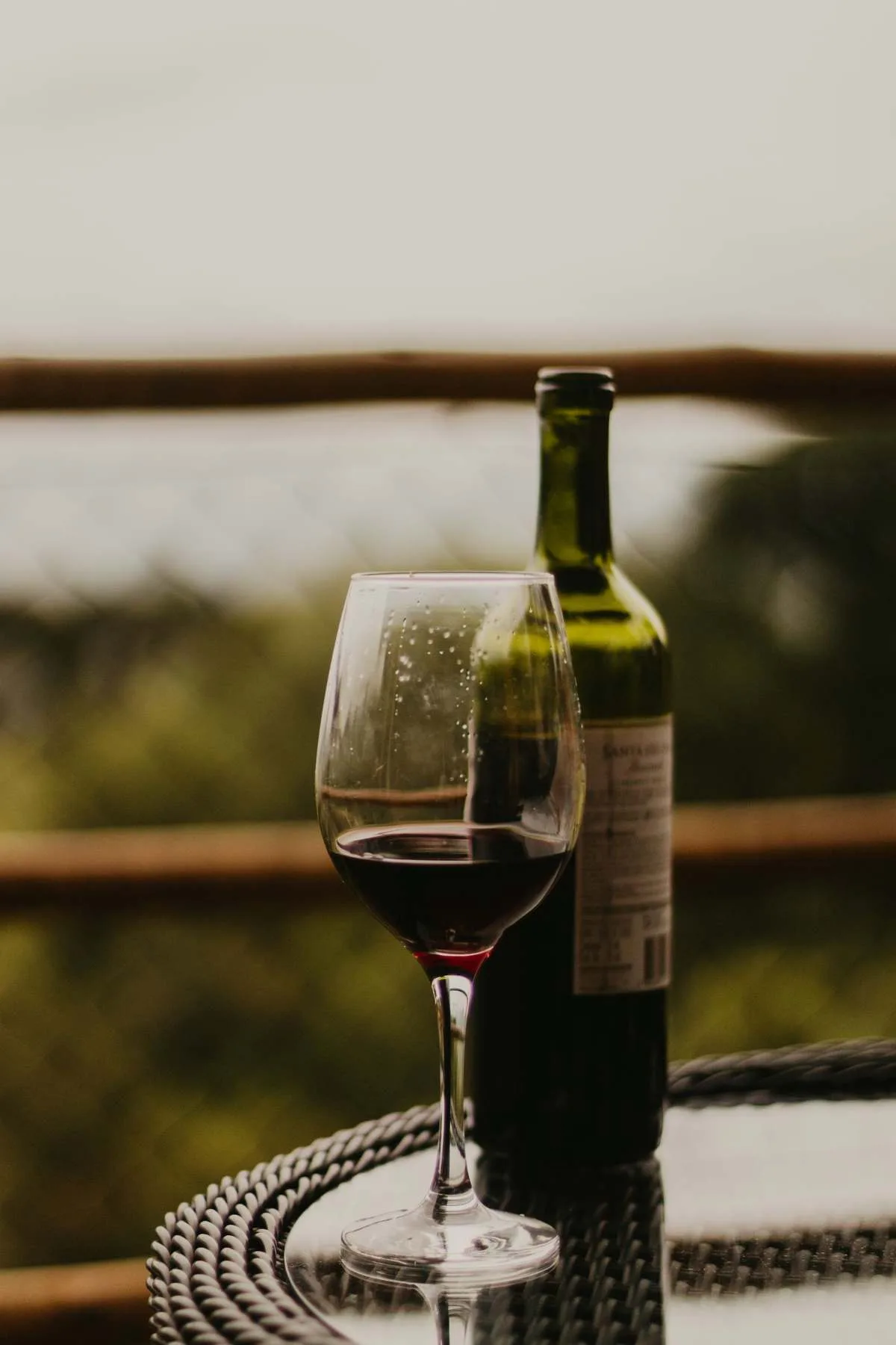 Glass of red wine and a bottle on an outdoor table