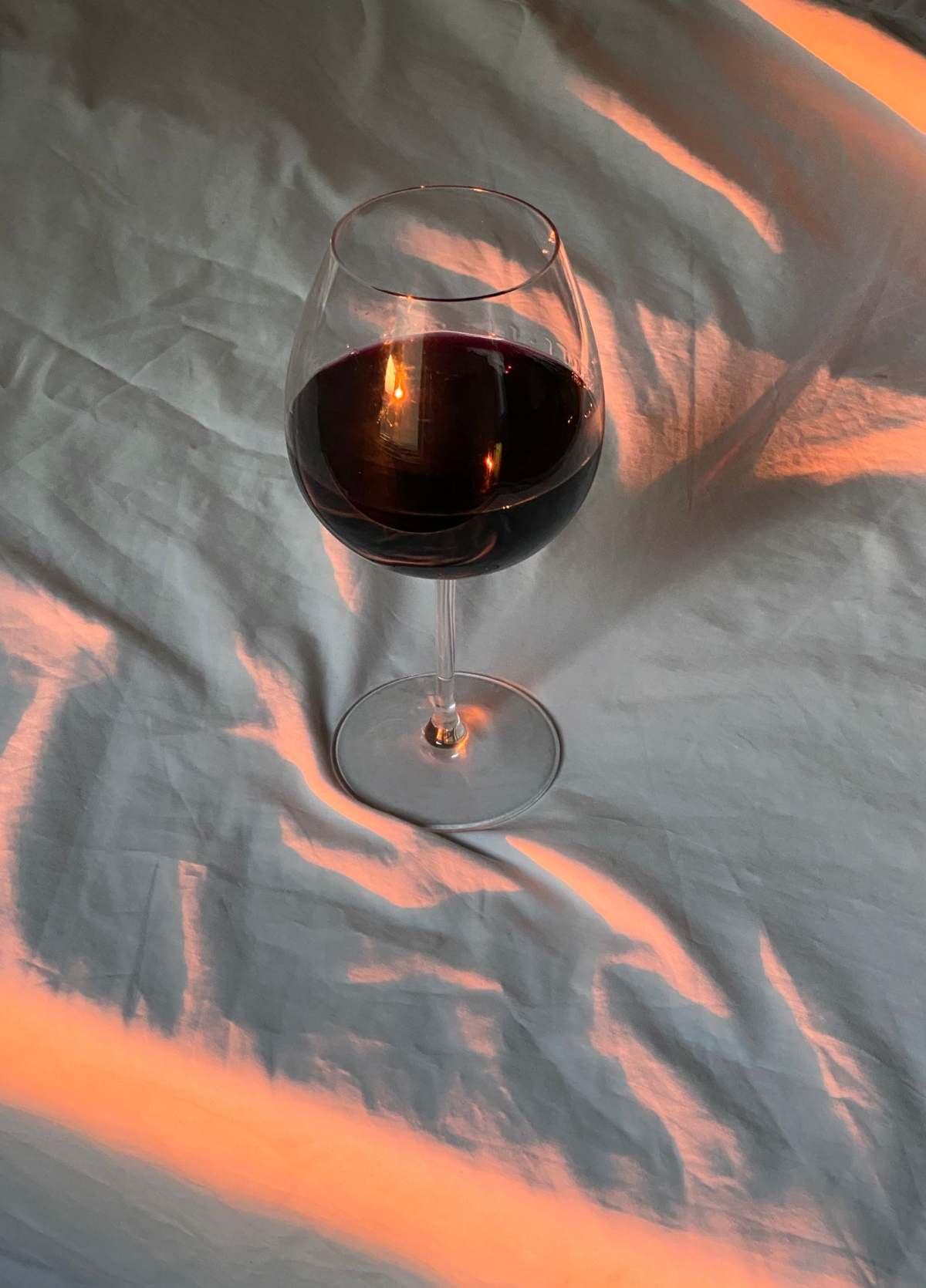 Tin City Wineries Paso Robles: 9 Must-Visit Tasting Rooms 21 Tin City wineries guide: glass of red wine resting on white linen in warm evening light