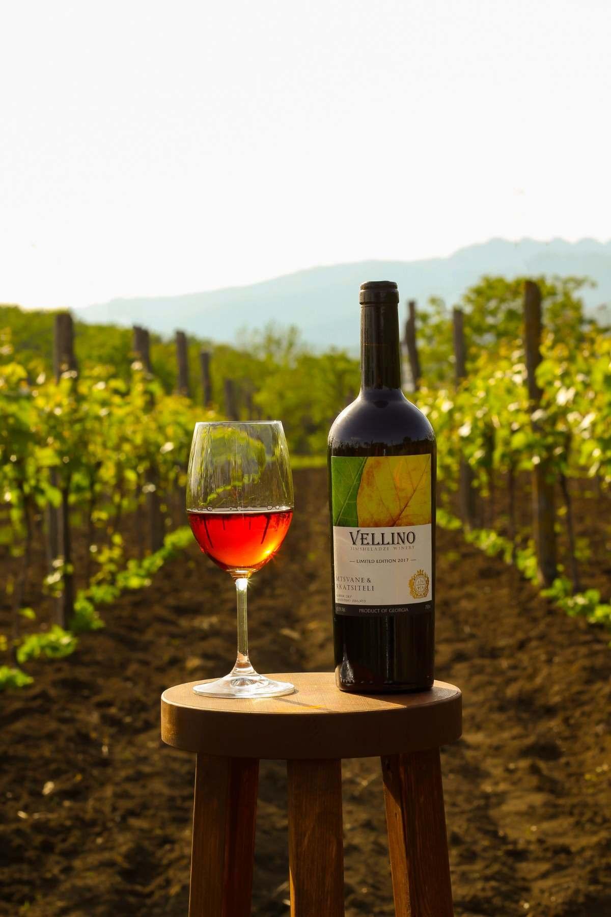 Wineries in Hocking Hills: Your Guide to Tasting Adventures 14 Wineries in Hocking Hills guide: glass of wine and a bottle on a wooden stool between vineyard rows