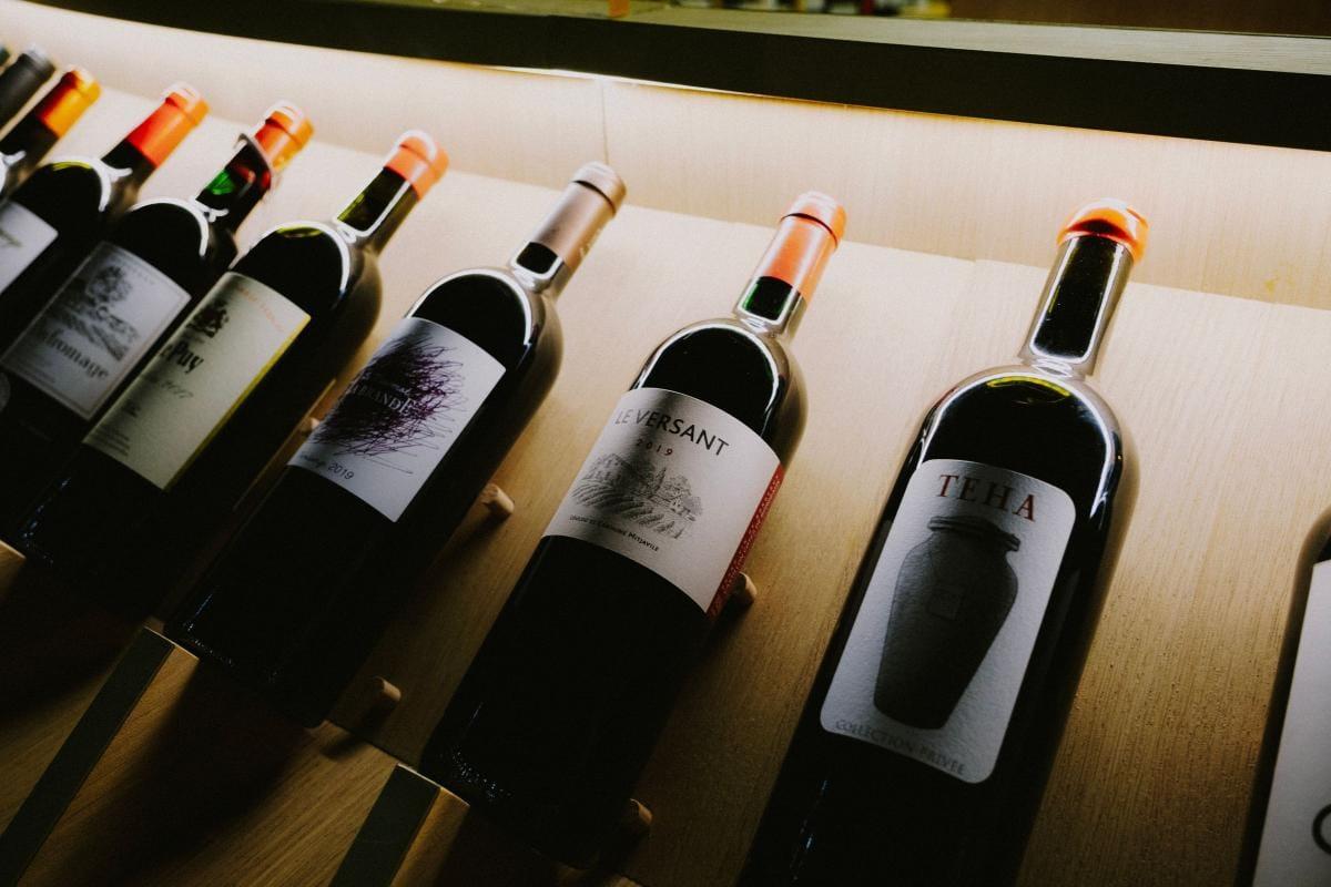 Bottles of red wine lying on a wooden shelf in soft light