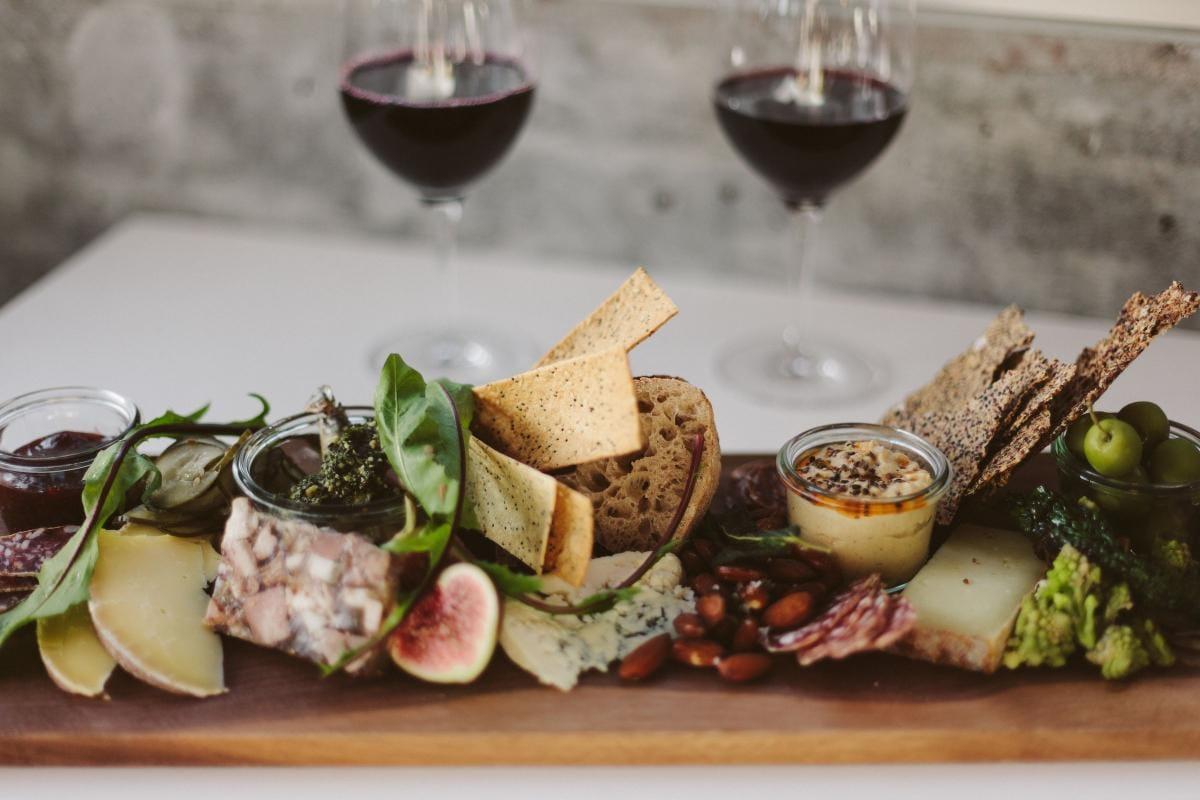 Best Wineries in Saratoga Springs NY: 9 Must-Visit Tasting Rooms 3 Two glasses of red wine behind a long wooden board of cheese, cured meats, figs and crackers