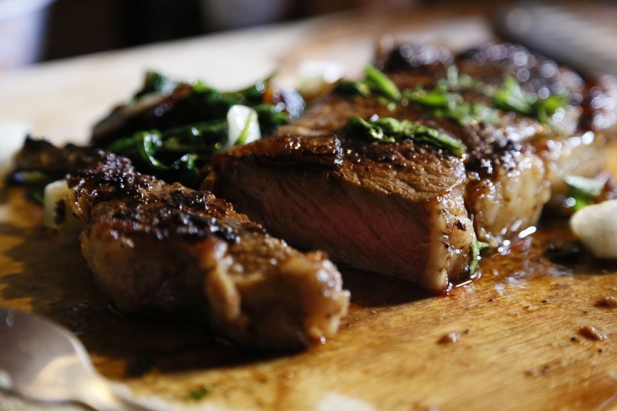 Close-up of sliced seared steak with chopped herbs on a plate