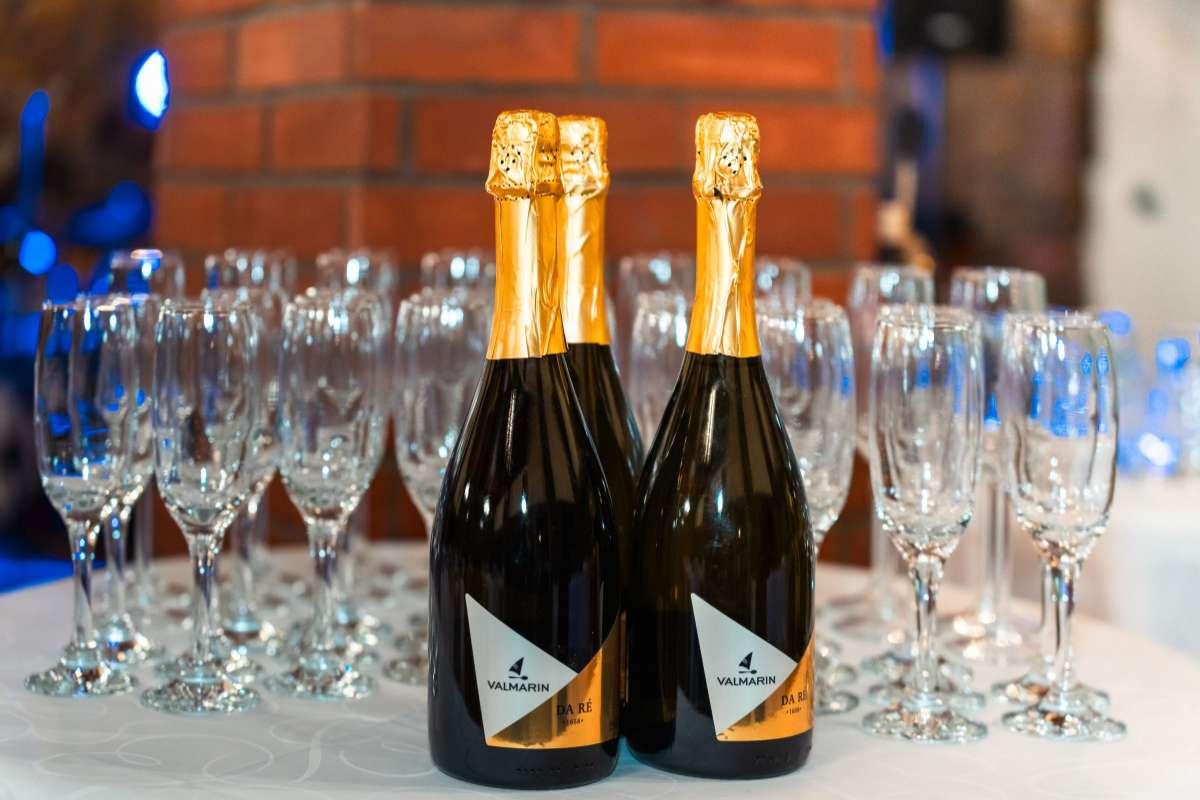 Types of Wine: 5 Main Styles You Need to Know First 3 Two bottles of sparkling wine in front of rows of empty flutes