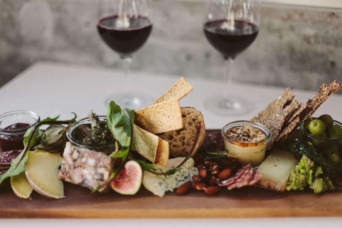 Gifts for Wine Lovers: 24 Picks Priced for 2026 2 Cheese and charcuterie board with two glasses of red wine behind it