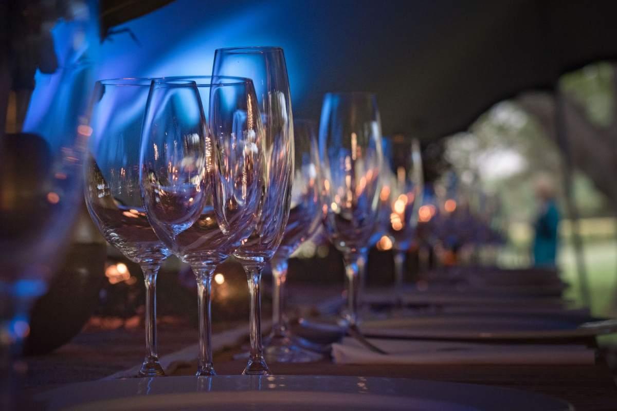 Gifts for Wine Lovers: 24 Picks Priced for 2026 3 Row of empty wine glasses on a dining table under blue light